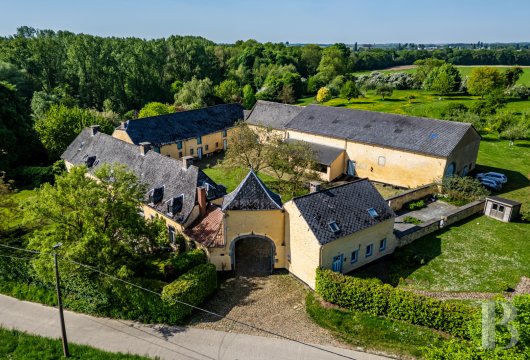 In Flanders, a traditional blond brick farmhouse and its outbuildings around the paved courtyard.