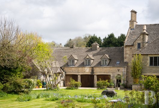 In a historic Cotswold village, a 13th-century manor house with preserved medieval and Tudor features, landscaped ...